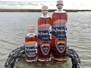 Bild zeigt 3 Flaschen Rum Ron Zuarin Classic in drei verschiedenen Größen Im Hintergrund ist die Ostsee bei Zingst